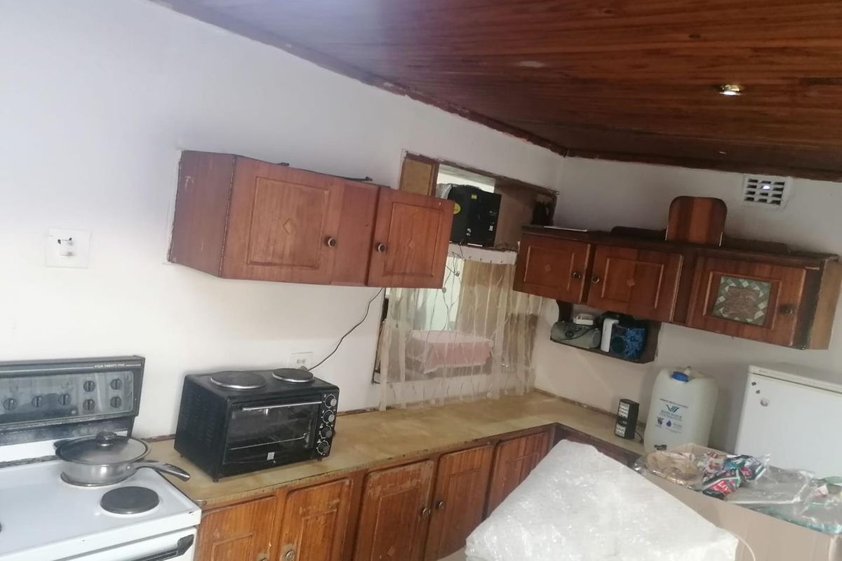 A dated kitchen featuring timber cabinetry, a wood-paneled ceiling, and a functional layout with built-in stove and oven.