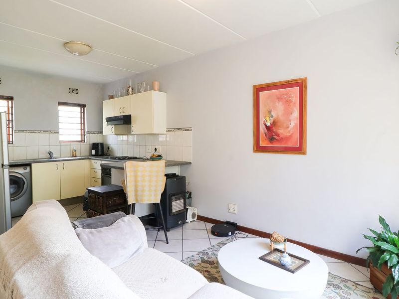 Open-plan living area featuring a functional kitchen with built-in cabinetry, tiled flooring, and a tiled backsplash, seamlessly connecting to the living space.