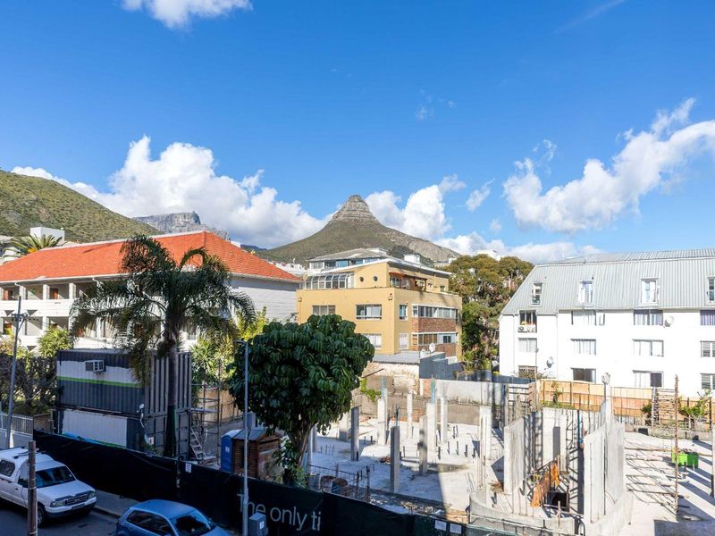 An elevated view overlooking a neighbourhood with surrounding apartment buildings and a prominent mountain peak in the background.