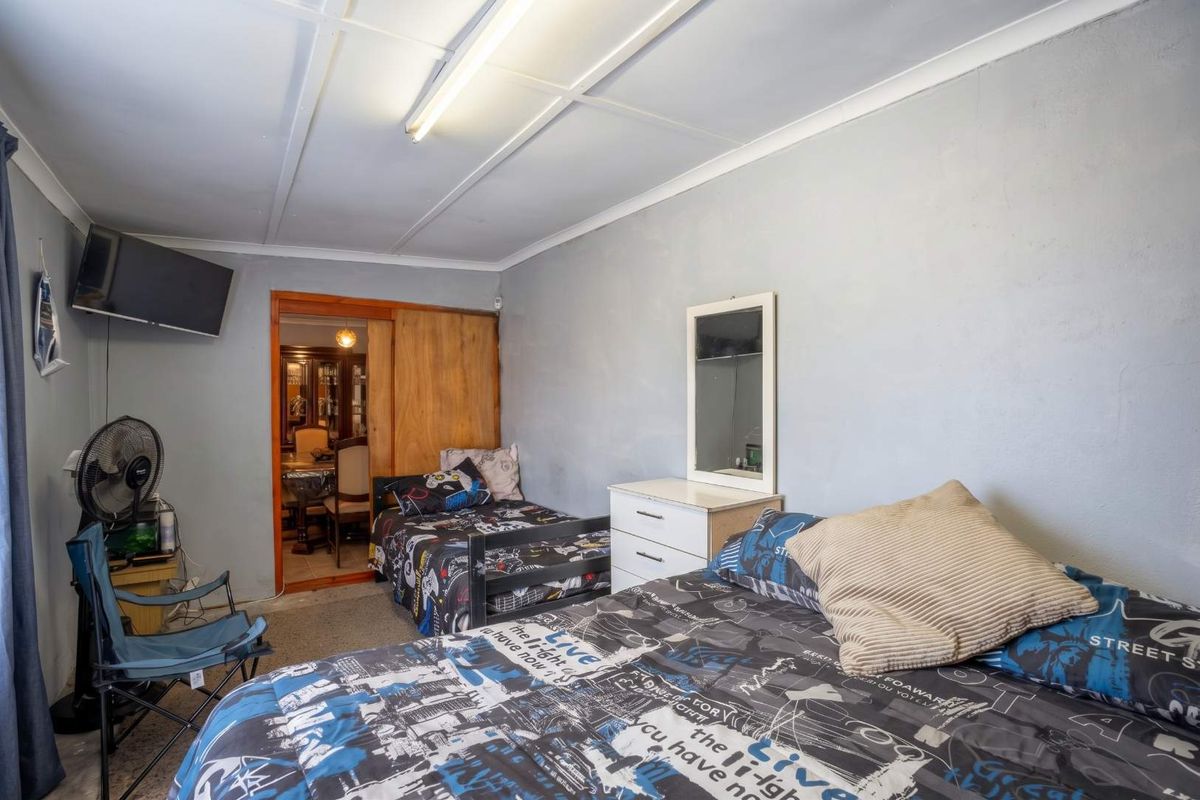 A bedroom featuring a sliding door entrance, textured ceiling tiles, and a fluorescent light fixture, offering a functional space with potential for cosmetic updates.