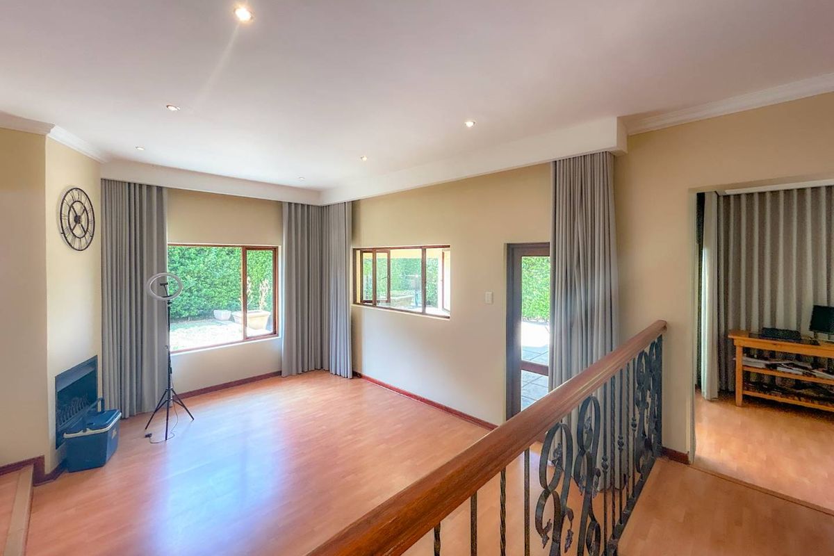 A spacious living area featuring laminate flooring, recessed ceiling lighting, and a decorative wrought iron balustrade overlooking the lower level.