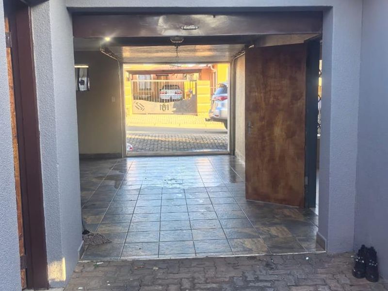 A functional garage space featuring tiled flooring and direct access to the paved driveway area.
