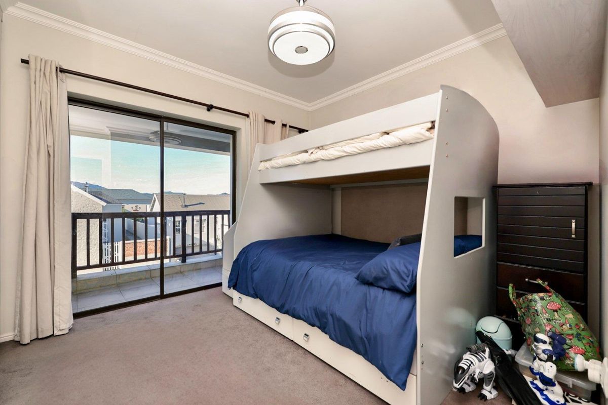 A well-maintained bedroom featuring neutral carpeting, crown molding, and a large sliding glass door providing access to a private balcony.