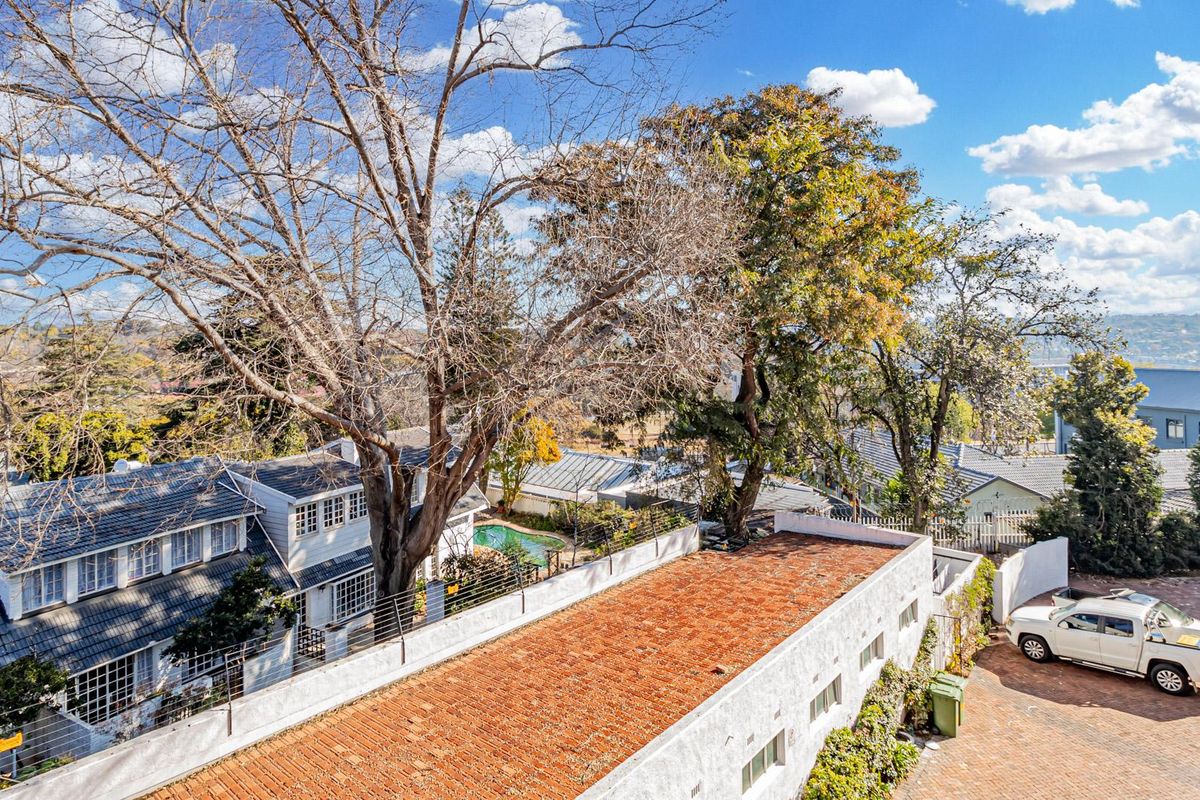 Aerial view of the property showing the roof structure, paved driveway, and surrounding residential landscape.