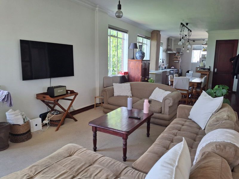 An open-plan living and dining area featuring a connected kitchen space with built-in cabinetry and neutral finishes throughout.