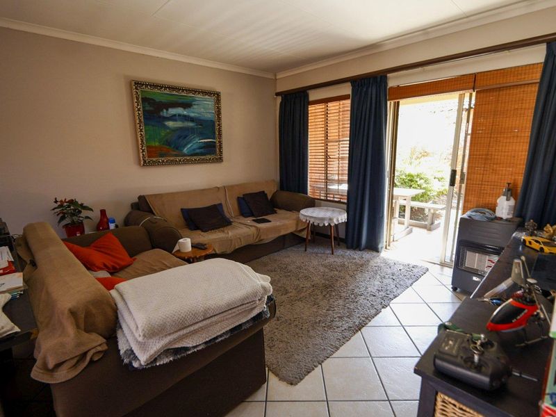 A comfortable living room featuring tiled flooring and a sliding glass door that provides direct access to the outdoor patio area.