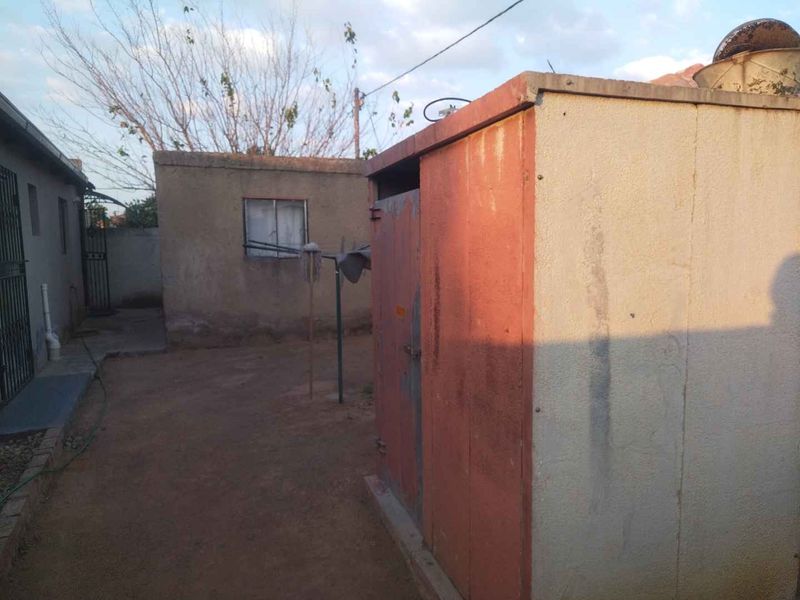 A view of the rear yard featuring a small outbuilding with weathered finishes and basic concrete ground surfacing.