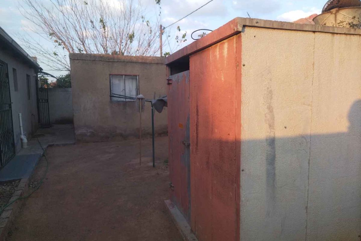 A view of the rear yard featuring a small outbuilding with weathered finishes and basic concrete ground surfacing.