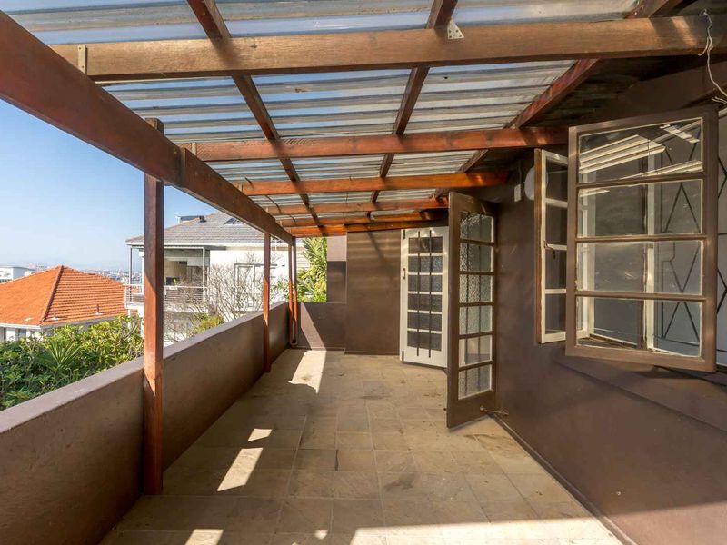 A covered balcony featuring a timber pergola, tiled flooring, and direct access to the interior, offering an elevated outdoor space with neighbourhood views.