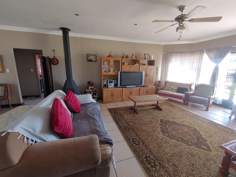 Spacious living room featuring tiled flooring, a freestanding fireplace, and a ceiling fan, offering a comfortable and functional family space.