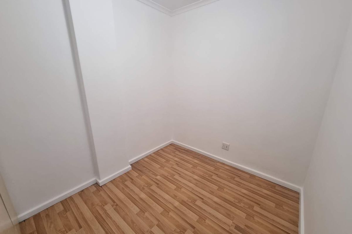A clean, empty bedroom featuring light wood-look laminate flooring and neutral white walls, providing a versatile blank canvas for any interior design style.