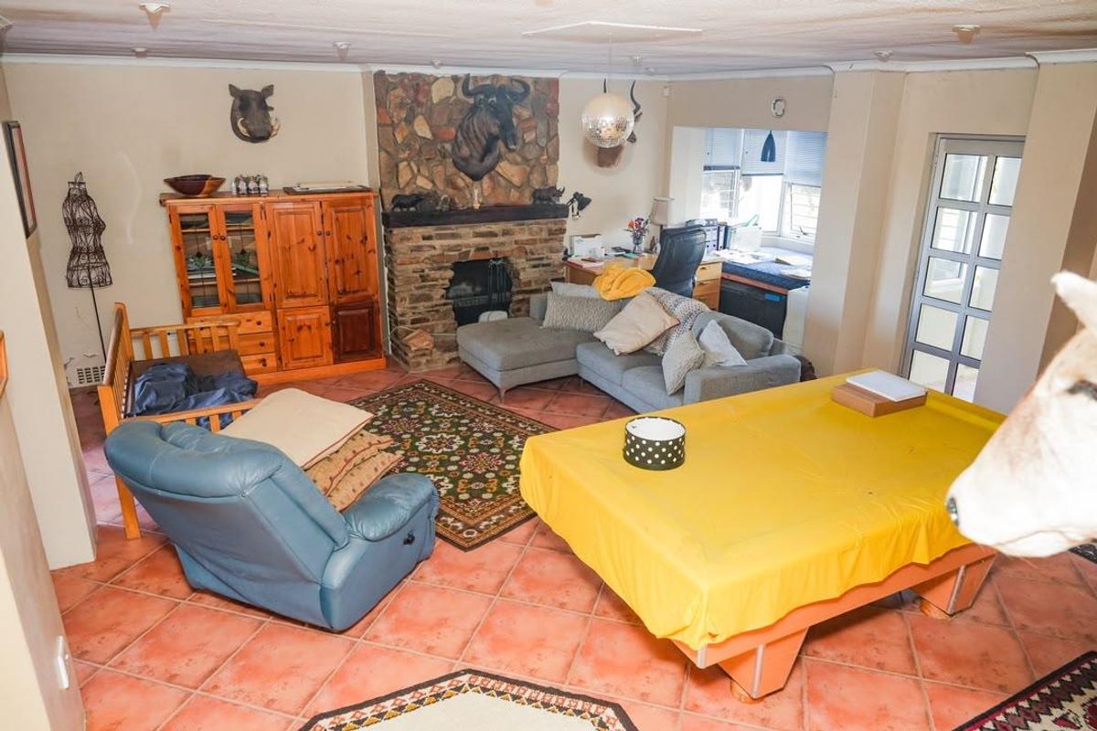 Spacious living room featuring a prominent stone fireplace, terracotta floor tiles, and direct access to the exterior through a glass panel door.