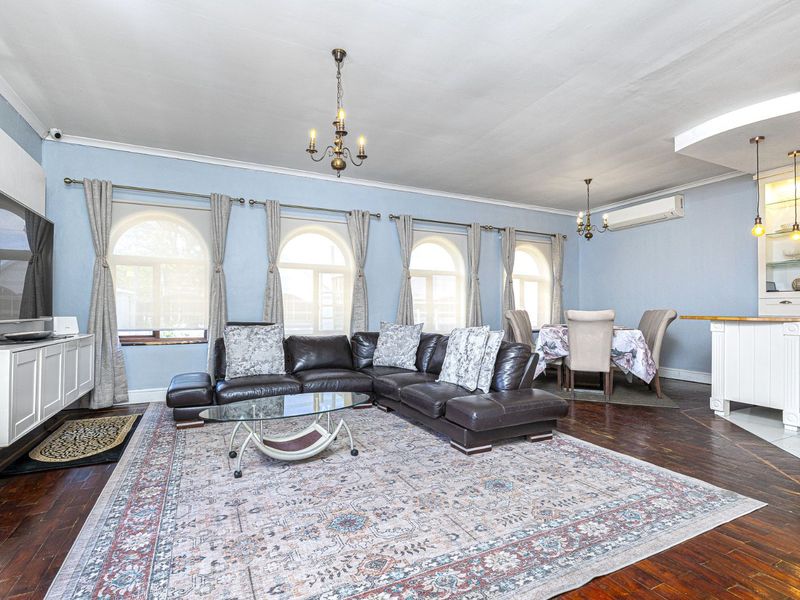 Spacious open-plan living and dining area featuring hardwood floors, arched windows, and built-in cabinetry, creating a bright and functional living space.