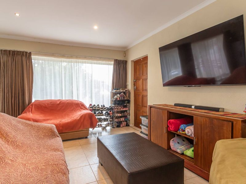 A functional living room featuring tiled flooring, recessed downlighting, and a timber entrance door, providing a comfortable and practical living space.