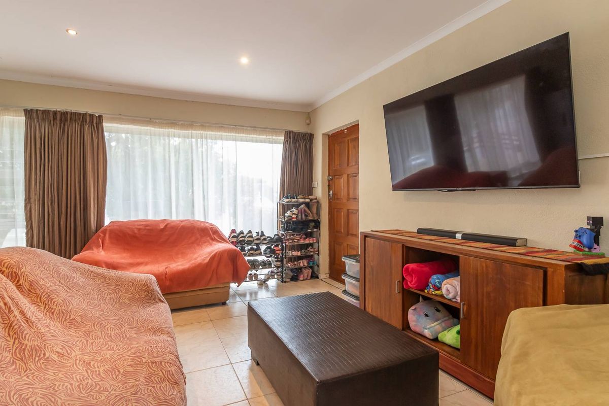 A functional living room featuring tiled flooring, recessed downlighting, and a timber entrance door, providing a comfortable and practical living space.