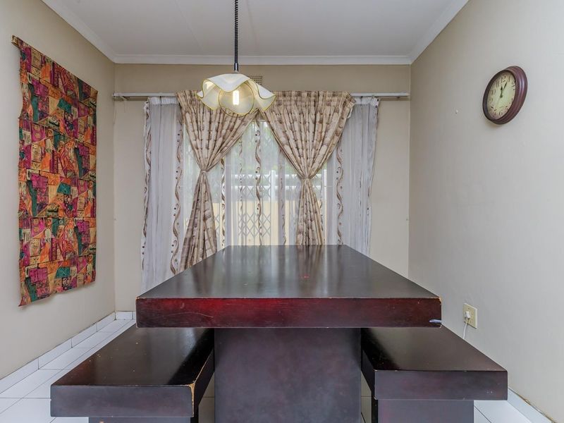 A functional dining area featuring tiled flooring and a central pendant light fixture, providing a neutral space for family meals.