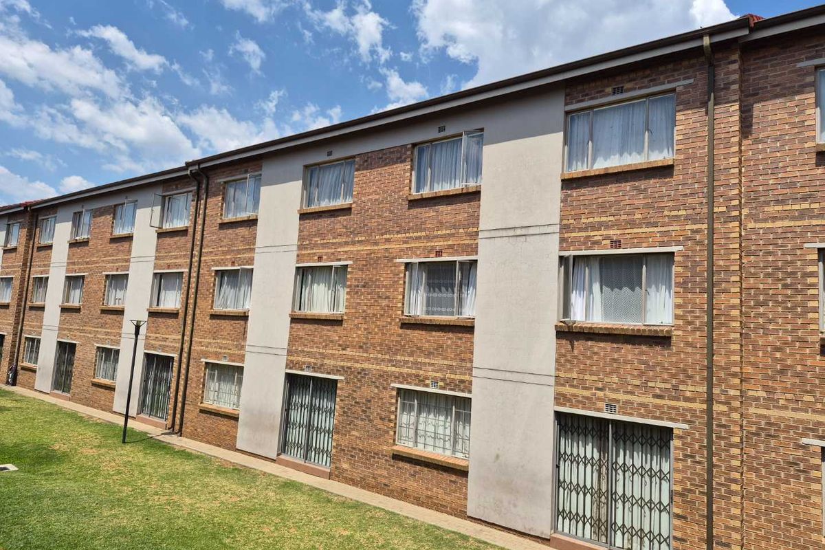 Exterior view of a multi-story apartment building featuring face brick facade, aluminium window frames, and ground floor sliding doors with security gates.