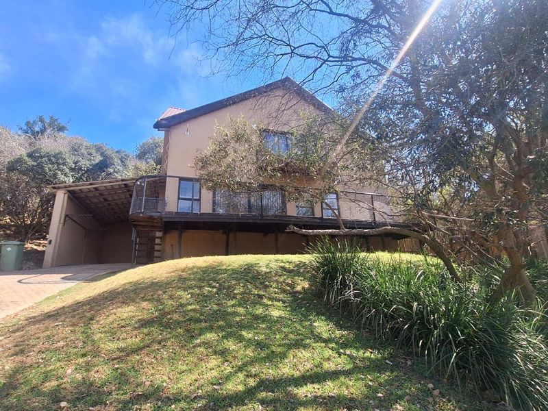 Rear view of the property featuring a raised wooden deck with metal railings, a spiral staircase, and an attached carport.