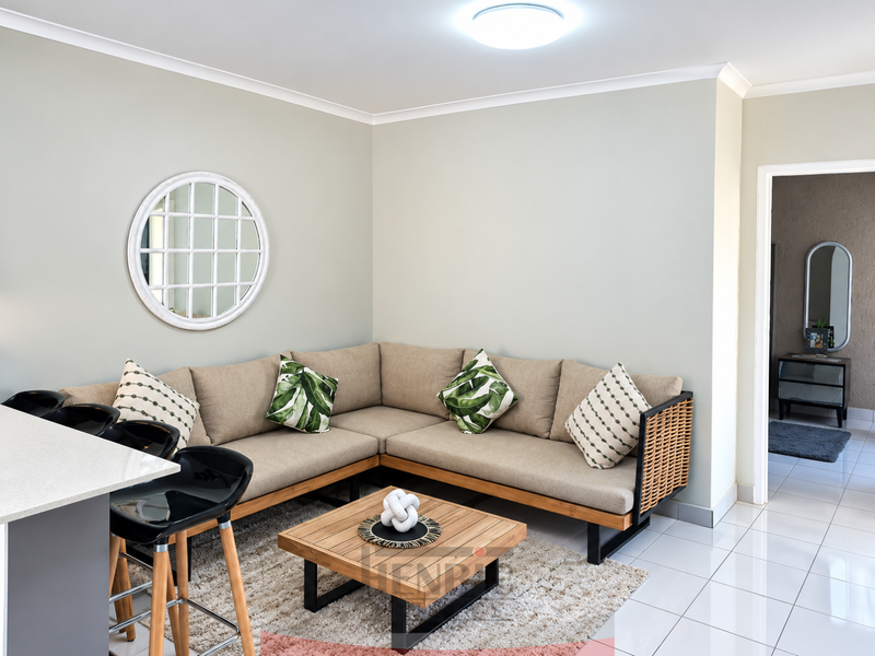 An open-plan living area featuring tiled flooring, a kitchen island with a quartz countertop, and neutral wall finishes.