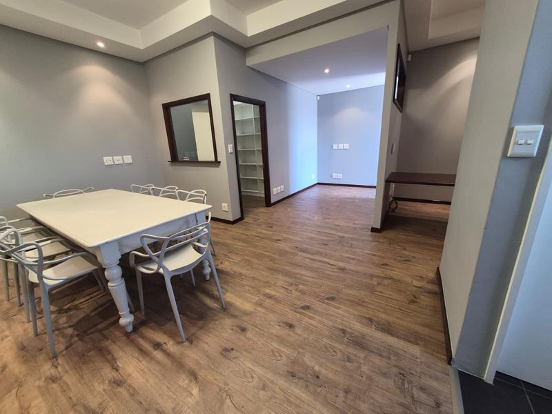 A modern office space featuring durable laminate flooring, recessed lighting, and a convenient pass-through window connecting to an adjacent room.