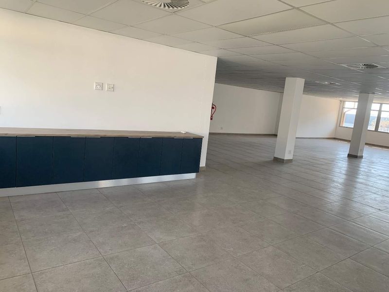 Spacious open-plan industrial office area featuring tiled flooring, a suspended ceiling, and built-in cabinetry, offering a versatile and clean workspace.