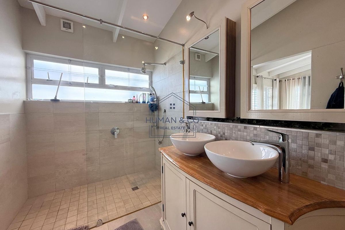 Modern bathroom featuring a double vanity with vessel sinks, a walk-in shower with glass enclosure, and neutral tiled finishes.