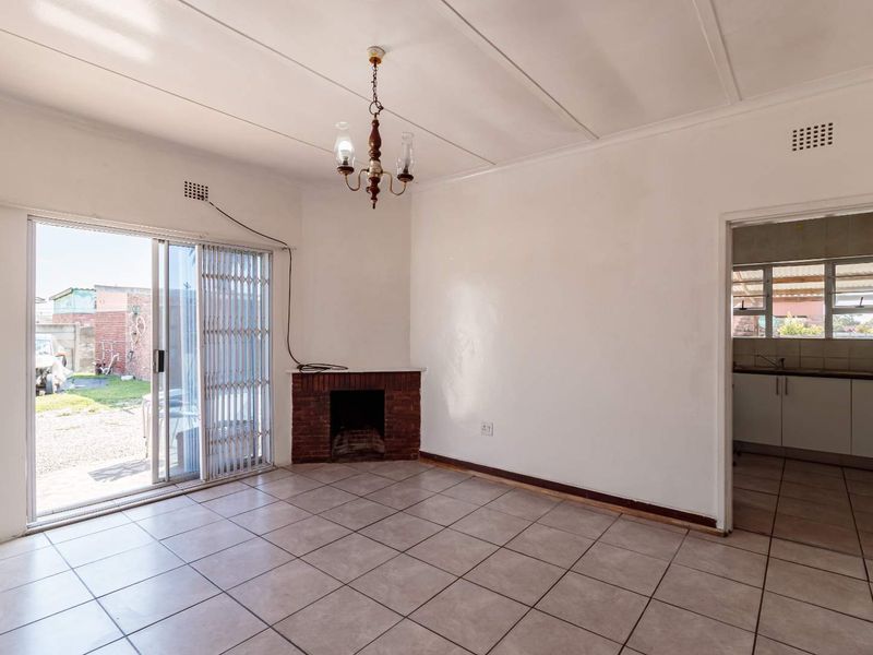 An empty living room featuring tiled flooring, a brick fireplace, and a sliding glass door providing access to the rear exterior.