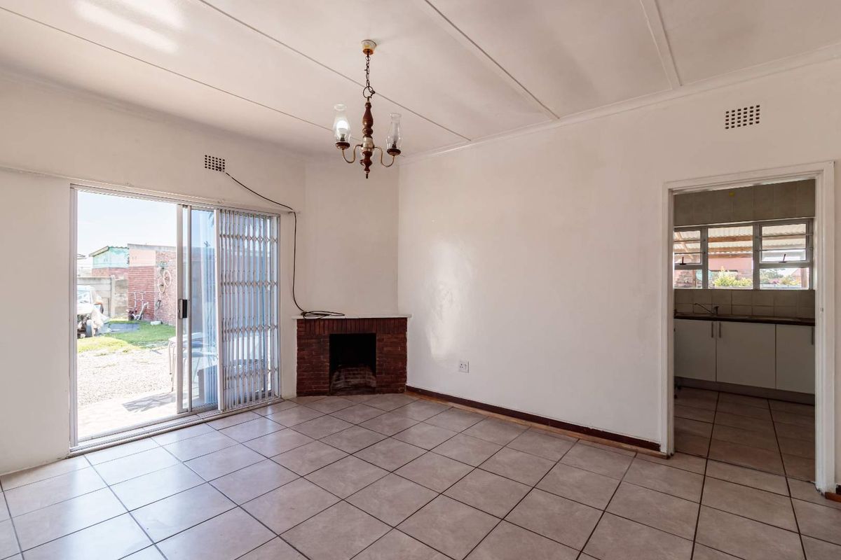An empty living room featuring tiled flooring, a brick fireplace, and a sliding glass door providing access to the rear exterior.