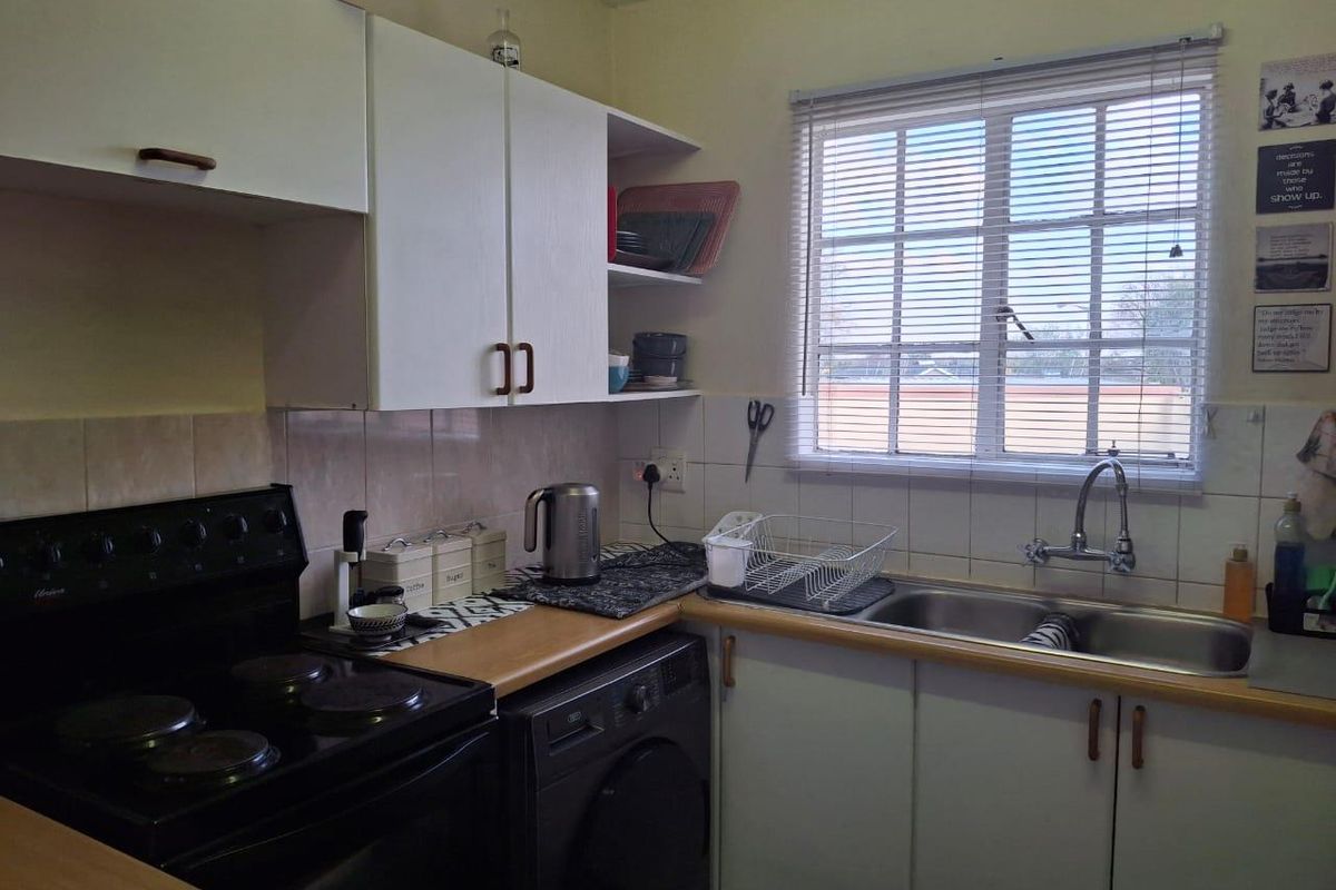 A functional kitchen featuring laminate countertops, a double stainless steel sink, built-in cabinetry, and space for a washing machine.