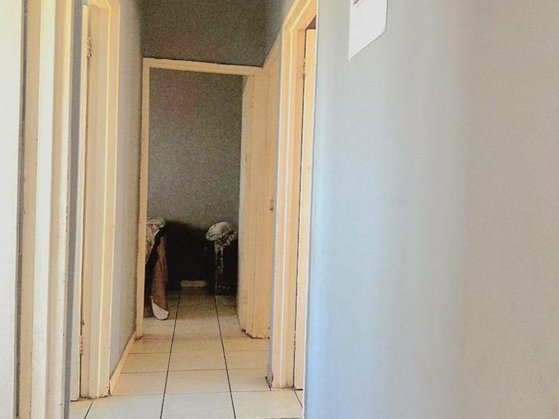 A functional hallway featuring tiled flooring and access to multiple rooms, with visible wear on the wall finishes and door frames.