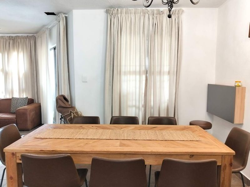 Dining area featuring tiled flooring, a wrought iron chandelier, and a wall-mounted storage unit, with access to adjacent living space.