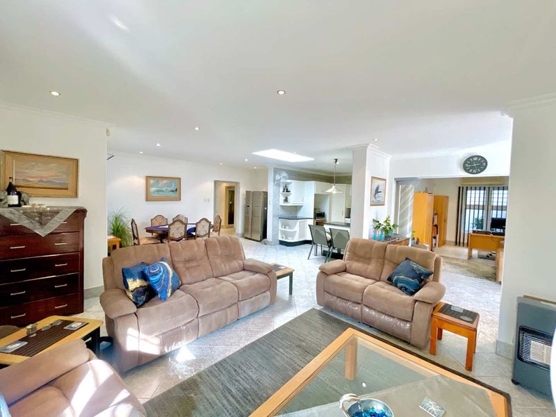 Spacious open-plan living area featuring tiled floors, recessed lighting, a skylight, and an integrated kitchen with built-in cabinetry and appliances.