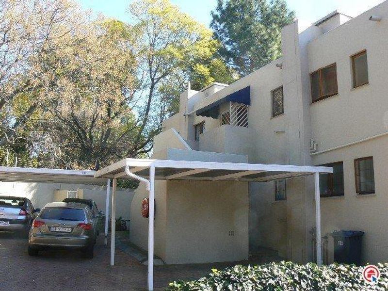 Exterior view of an apartment building featuring a covered carport, external staircase, and a small balcony.