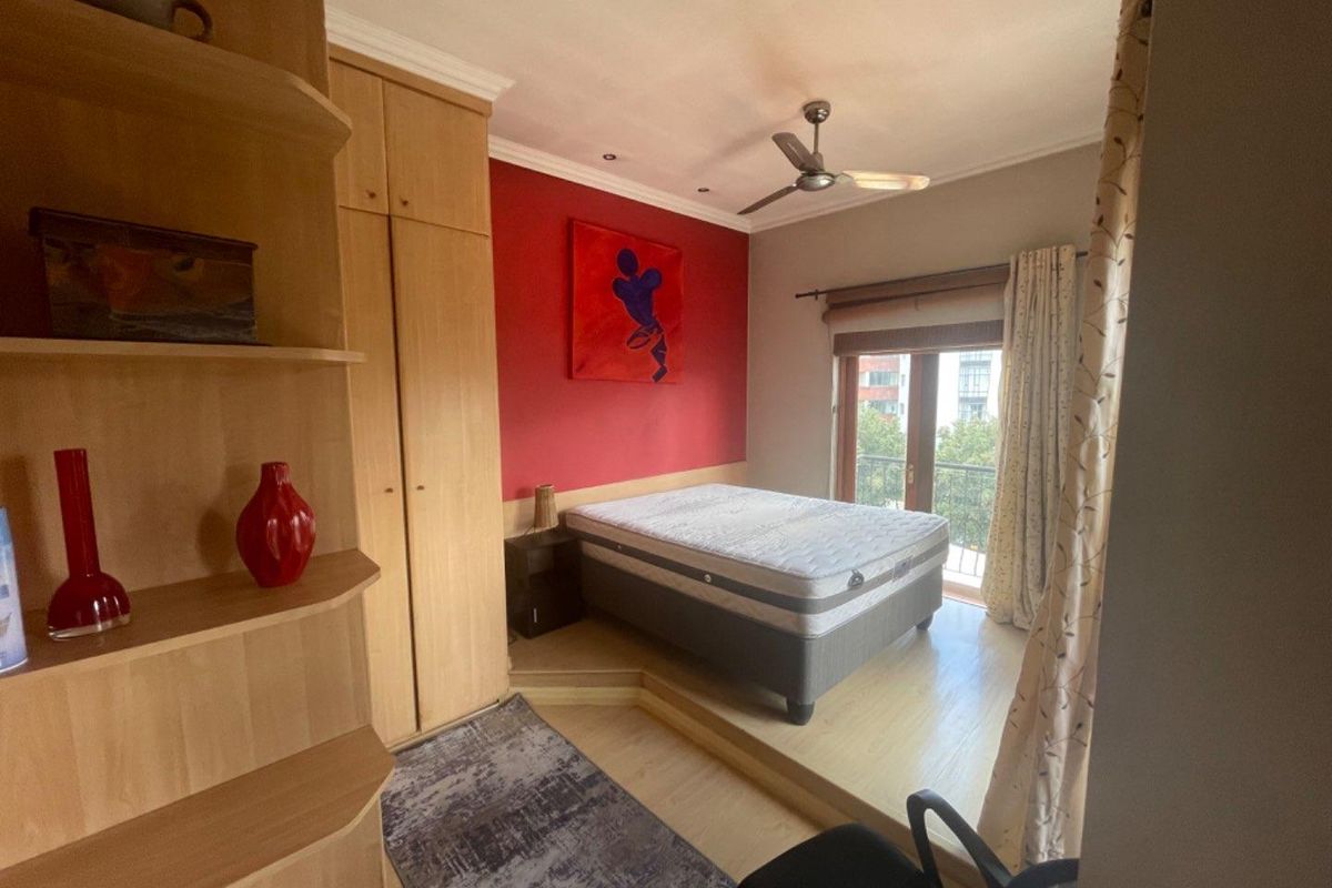 Bedroom featuring a raised platform area, built-in wooden cabinetry, ceiling fan, and access to a private balcony.