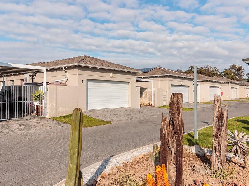 Front view of a townhouse complex featuring paved driveways, sectional garage doors, and well-maintained exterior finishes.