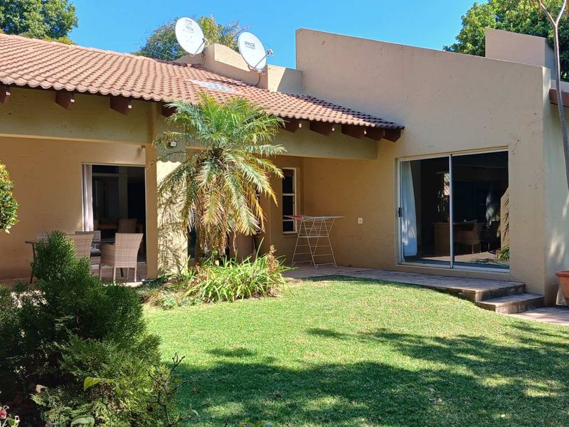 Rear view of the house featuring a covered patio, sliding glass doors, and a well-maintained garden area.
