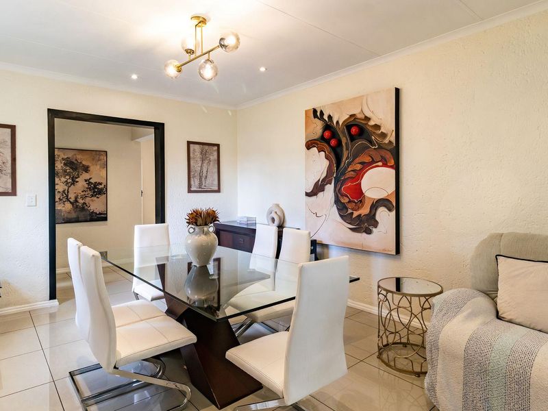 A bright and well-maintained dining room featuring polished tiled flooring, a modern chandelier, and recessed lighting, creating a clean and inviting atmosphere.