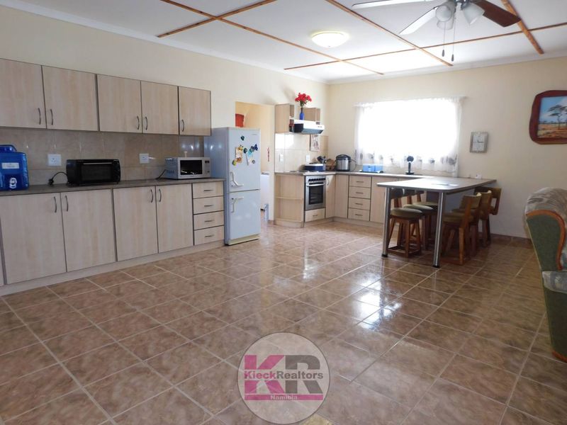 Spacious kitchen featuring laminate cabinetry, built-in oven, hob, extractor fan, tiled flooring, and an integrated breakfast nook area.