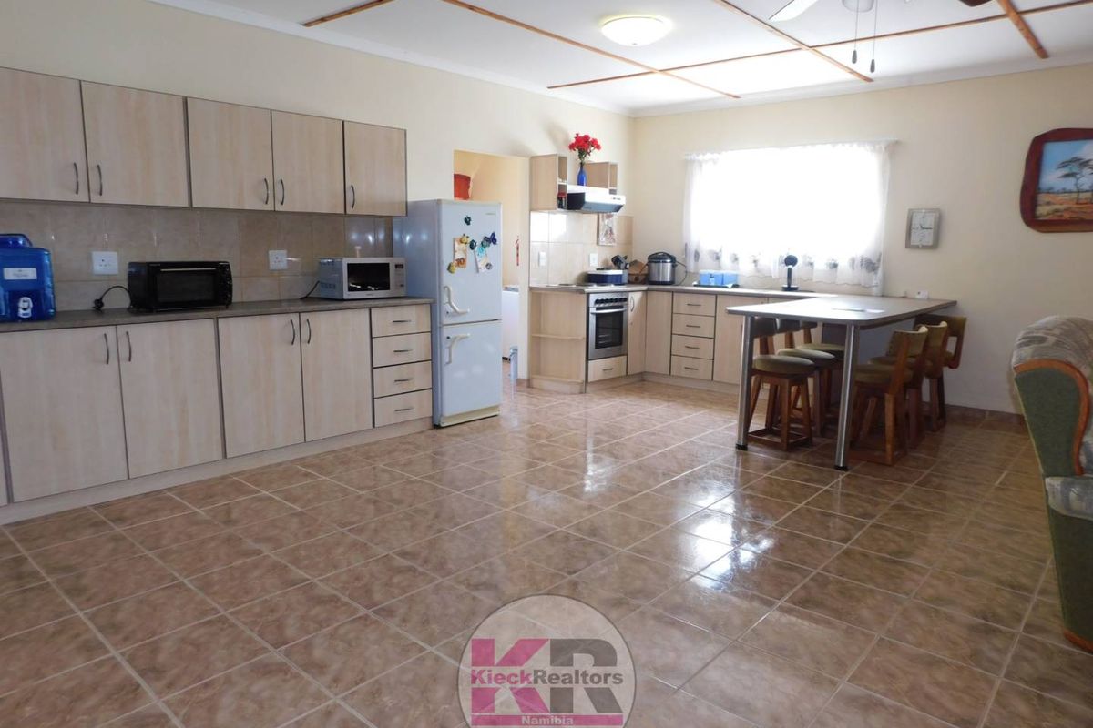 Spacious kitchen featuring laminate cabinetry, built-in oven, hob, extractor fan, tiled flooring, and an integrated breakfast nook area.