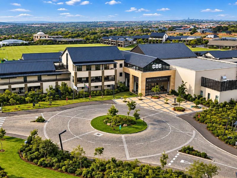 Aerial view of the Steyn City School campus featuring a paved roundabout, extensive landscaped grounds, and modern multi-story educational facilities.