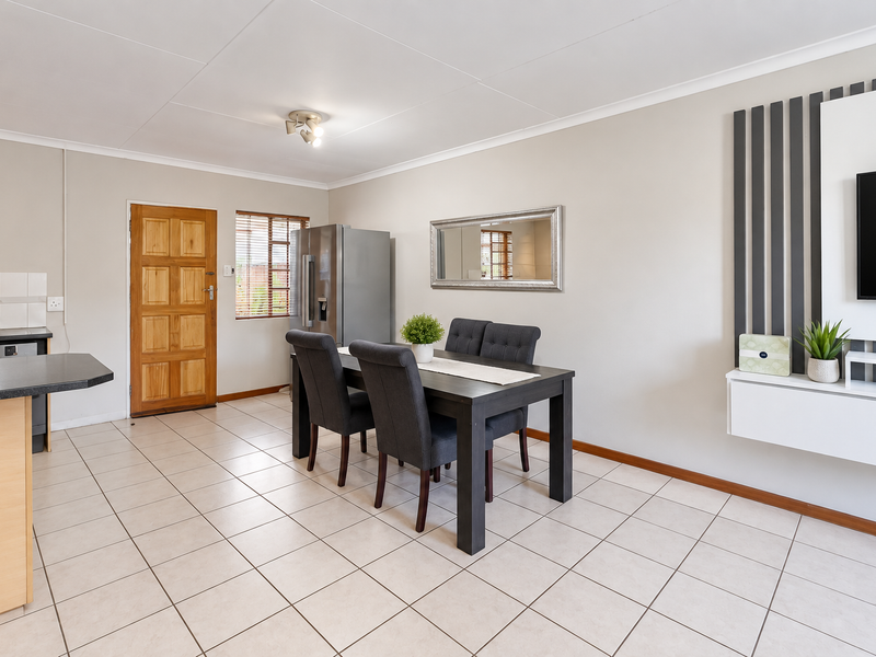 Open plan living and dining area featuring tiled flooring, a modern built-in wall unit, and direct access to the kitchen space.