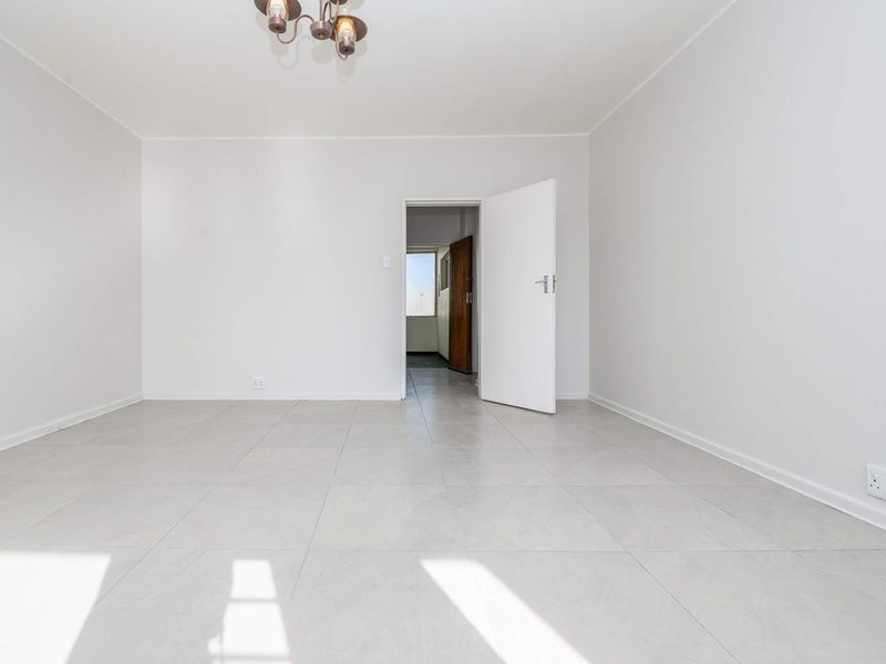 A bright, empty bedroom featuring neutral tiled flooring and clean white walls, providing a versatile blank canvas for interior design.