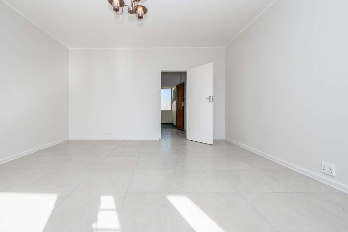 A bright, empty bedroom featuring neutral tiled flooring and clean white walls, providing a versatile blank canvas for interior design.