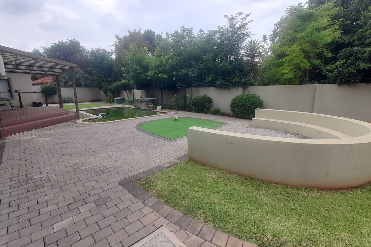 Rear garden featuring a paved patio area, built-in curved seating, a swimming pool, and a covered deck space.