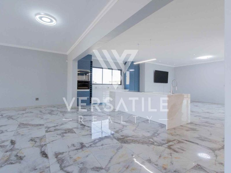 Spacious open-plan living and kitchen area featuring high-end marble-look floor tiles, a modern kitchen island, and sleek built-in cabinetry.