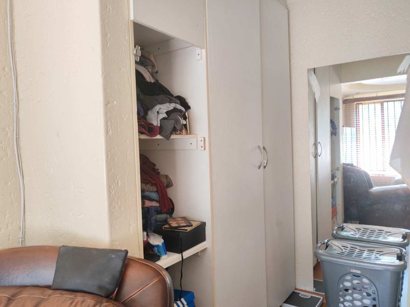 Bedroom featuring built-in cupboards with a mirrored door, providing storage space. The room shows signs of wear and requires cosmetic updates.