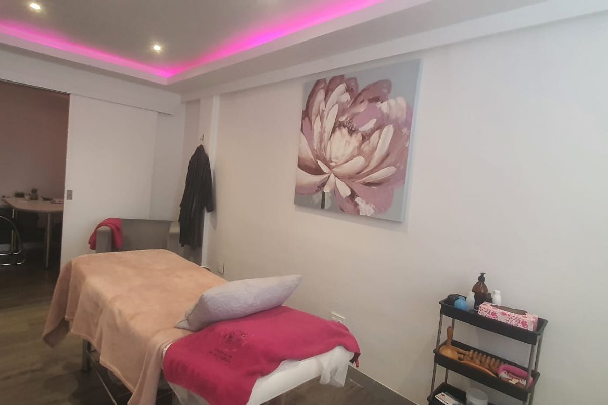 A treatment room featuring recessed ceiling lighting with integrated cove lighting, laminate flooring, and a sliding door leading to an adjacent space.