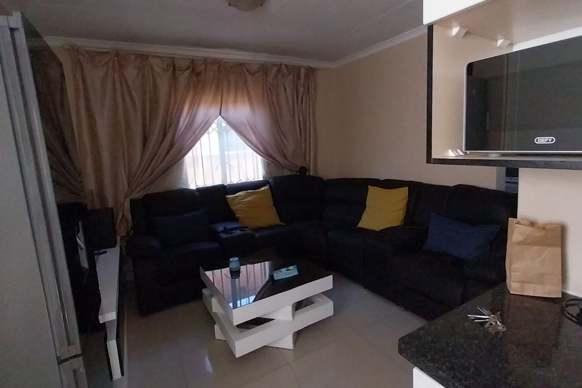A compact living area featuring tiled flooring and a built-in kitchen counter section, providing a functional space for relaxation.