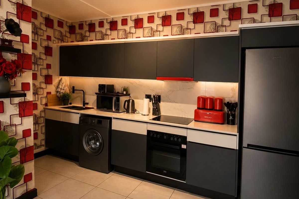 Modern kitchen featuring dark cabinetry, integrated appliances, marble-effect splashback, and contemporary track lighting, complemented by patterned feature wallpaper.