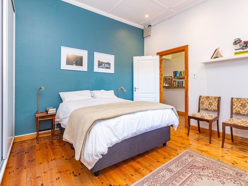 A well-maintained bedroom featuring polished timber flooring, a bold blue accent wall, and built-in wardrobe storage.